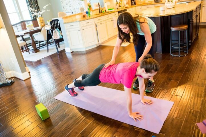 PT adjusts form of woman holding the plank position