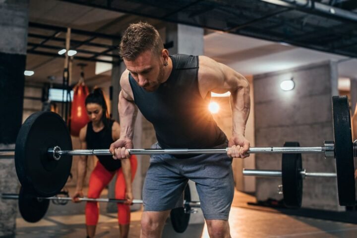 Three people in the gym performing the reverse-grip bent-over row exercise with barbells