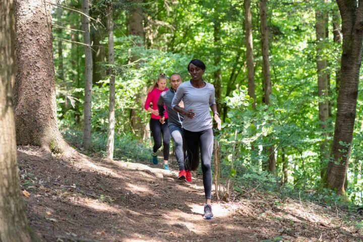Group of three people running through a forest