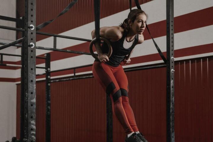 A woman performing a ring muscle-up in a CrossFit gym