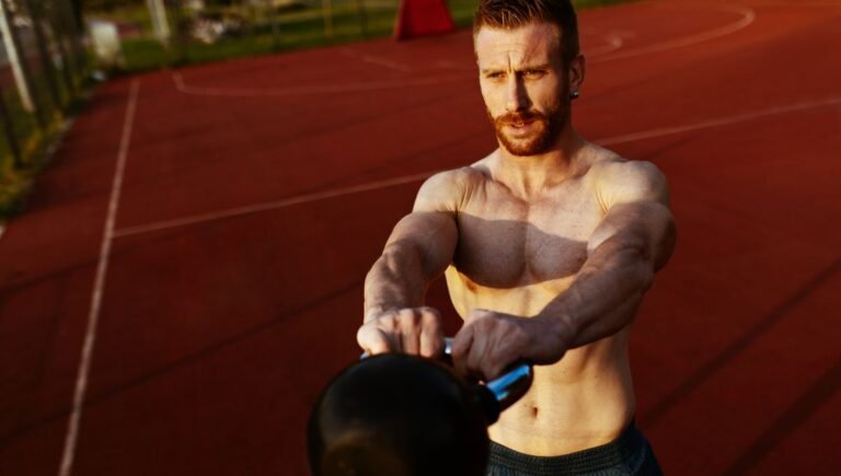 Shirtless man performing kettlebell swing