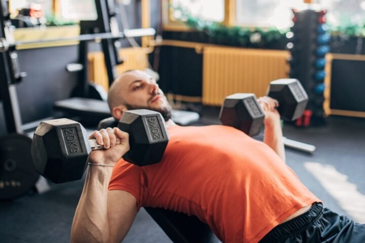 Man performing incline bench press with dumbbells