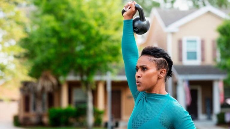 Woman presses kettlebell overhead