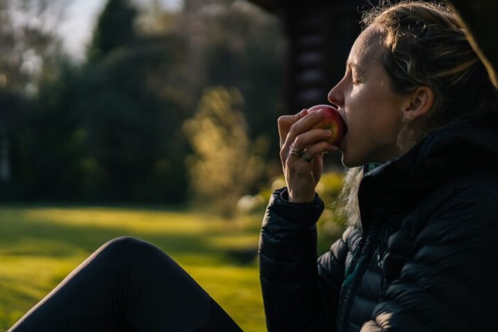 Woman sitting outside eating an apple