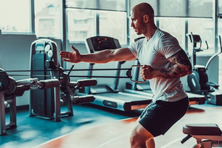 Man performing single-arm cable row in gym