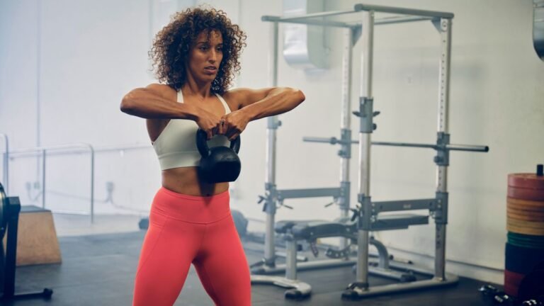 Woman performs upright row exercise with a kettlebell in the gym