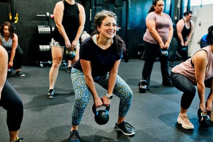 Group of women in gym performing kettlebell deadlift